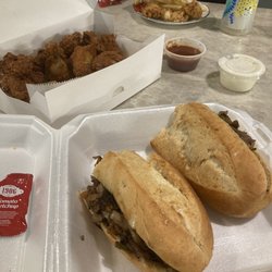 Philly's Pizza - Front to back: 12" cheesesteak, 12-piece Chicken Wings and Fries with BBQ and Ranch sauces, and half of a 4-piece Chicken Strips and Fries.
