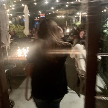 The Lark - Blurry image of the epic lighting and a fire pit on the vibeful outside patio. - New American Near Me - Santa Barbara, California