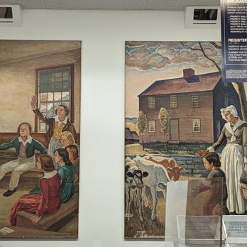 US Post Office - The image shows two large paintings mounted on a white wall inside a building. The left painting depicts a man in a suit addressing a group of seated individuals, with some raising their hands. The right painting portrays a woman in historical attire standing outdoors near a young boy and a cow, with a house and trees in the background. The setting appears to be an indoor exhibit or gallery space. - Post Offices Near Me - Torrington, Connecticut