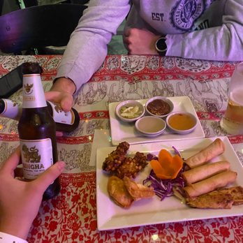 Thai Island - a person sitting at a table with a plate of food and a bottle of beer - Thai Near Me - Tampa, Florida Thai Island - a person sitting at a table with a plate of food and a bottle of beer - Thai Near Me - Tampa, Florida