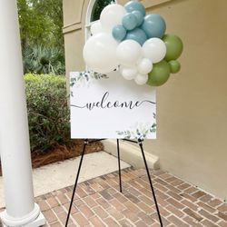 Palmetto Balloon - Dusty blue, sage, and white balloon "bomb" cluster flanks welcome sign at engagement party at Hobcaw Plantation Club House in Mount Pleasant