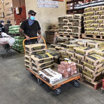 Flower Power Gardens - a man pushing a cart full of seed - Landscaping Near Me