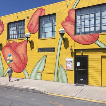 Bottle Works - a yellow building with a mural of red tulips - Art Galleries Near Me - Johnstown, Pennsylvania
