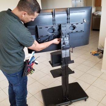 Smart Home Guys Tucson - Misael neatly tucking cords on back of TV stand. - TV Mounting Near Me - Tucson, Arizona