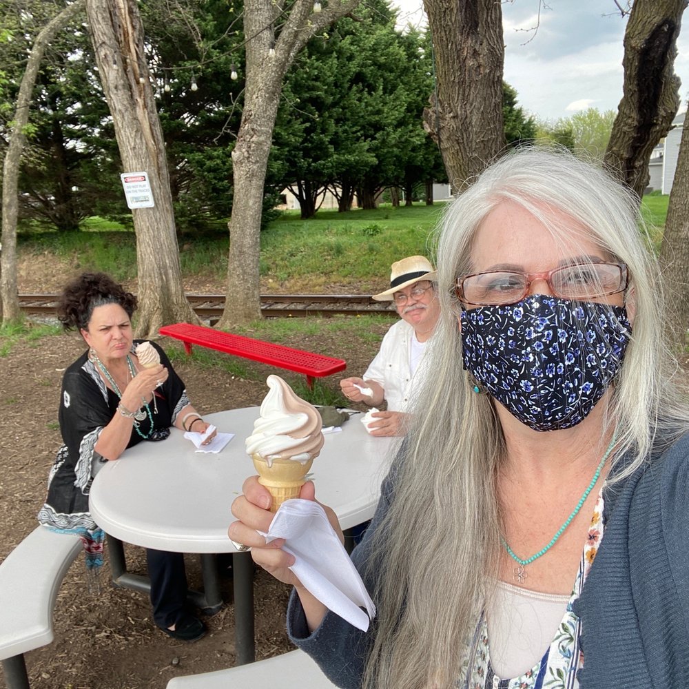 a woman wearing a face mask and eating an ice cream cone