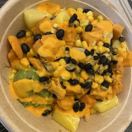 Southwest bowl - A bowl containing chunks of vegetables like squash and potatoes, topped with melted cheese and black beans, served in a disposable container.