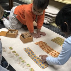 International Montessori - Math work being observed by a younger student in the mixed age environment