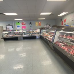 a man standing in front of a display of meat a man standing in front of a display of meat
