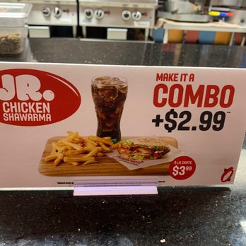Osmow's Shawarma - The sign advertises JR Chicken Shawarma, highlighting a combo meal option that includes fries, a soft drink, and a sandwich. The sign features the restaurant's logo, a picture of the meal, and pricing information, including a special combo price and a la carte option. The background shows a counter with kitchen equipment and supplies. - Mediterranean Near Me - Markham, Ontario