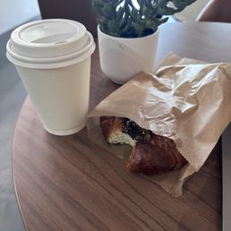 Americano and a bitten pretzel bagel