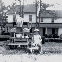 Farmers Daughter Gift & Garden Center - The beginning roadside stand in 1967 with Megan Shaub and her  American flag selling green beans by the side of the road.