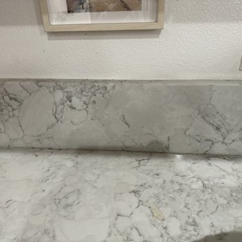Wave House Cleaning - Marble backsplash and countertop with an electrical outlet and a framed picture on the wall. - Home Cleaning Near Me