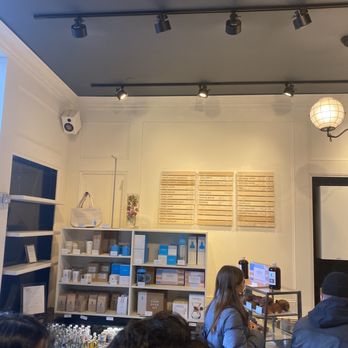 Blue Bottle Coffee - Bryant Park - The front of store and wall menu; as well as shelves with drinks and snacks, as well as coffee and merchandise you can take home! - Coffee & Tea Near Me - New York, New York