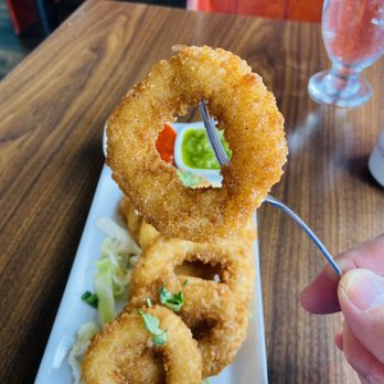 Kalai's Dosa Hut - a hand holding a fork and a plate of onion rings - Indian Near Me - Vancouver, British Columbia