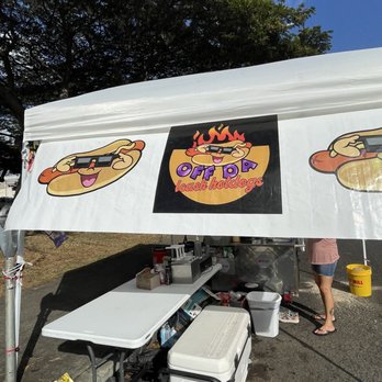 Off The Leash Hot Dogs - a man standing under a tent - Hot Dogs Near Me