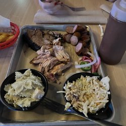 A trio plate of sausage, brisket, and sausage with sides of pickle pasta and slaw.