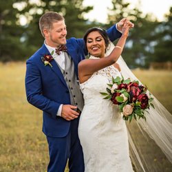 Compass Rose Floral - A groom twirling a bride in a field as she holds her bouquet