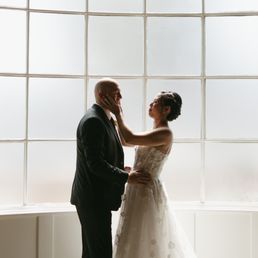 A dramatic, editorial silhouette of the couple's first kiss in front of the venue's signature floor-to-ceiling grid window. A dramatic, editorial silhouette of the couple's first kiss in front of the venue's signature floor-to-ceiling grid window.