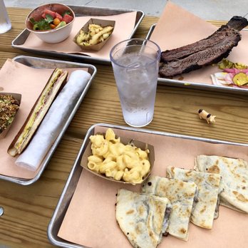 Wood's Chapel BBQ - Clockwise: spicy salads (watermelon & cucumber), beef rib, brisket quesadilla w/ Mac n cheese, & Cuban sandwich w/ pork belly fried rice - Barbeque Near Me - Atlanta, Georgia