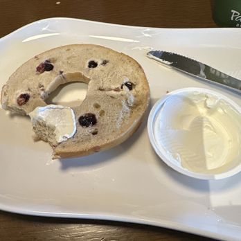 Panera Bread - Tough, stale bagel....., - A blueberry bagel with cream cheese spread is partially eaten on a white tray, with a butter knife and a container of cream cheese. - Salad Near Me - Union, Kentucky