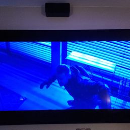 Hobbes & Shaw never looked so good! - A large flat-screen television mounted on a wall displays a scene with a person leaning forward, illuminated by blue lighting. The reflection of the person is visible on the screen, and the background includes window blinds and a light fixture. The image is taken indoors, with a date stamp of January 19, 2024, in the bottom right corner.