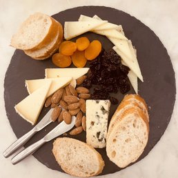 a plate of cheese, crackers, almonds, and dried apricots a plate of cheese, crackers, almonds, and dried apricots