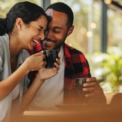 Healthwise Behavioral Health & Wellness - A happy couple sharing a warm moment and laughing together while drinking coffee, illustrating healthy communication and rela...