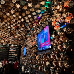 a bar with a lot of beer kegs hanging from the ceiling