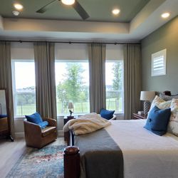 Budget Blinds of Southeast Austin and Hays County - Custom drapery and shutters to frame the windows in this primary suite in the Kissing Tree neighborhood in San Marcos, TX
