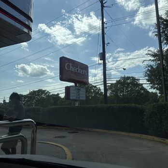 Checkers - Checkers restaurant sign seen outside with a blue sky, clouds, and power lines in the background. - Burgers Near Me - Gaithersburg, Maryland