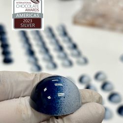 Chocs ‘N Boxes - Blueberry Compote Lychee Ganache bonbon, awardee at 2023 International Chocolate Awards- AMERICAS.
