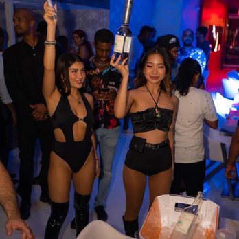 Koi Restaurant and Lounge - a woman in a bikini holding a bottle - Bars Near Me - Washington, DC, District of Columbia