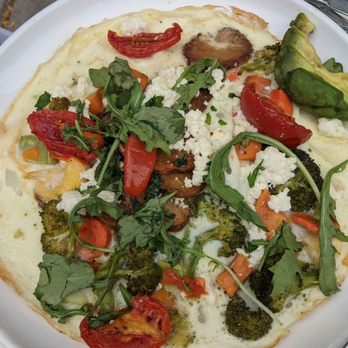 Sava's - A vegetable pizza with toppings such as cherry tomatoes, broccoli, arugula, and cheese on a thin crust. - Bars Near Me - Ann Arbor, Michigan