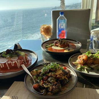Raya - All our orders brought out at once. Brussels Sprouts, Piloncillo Shrimp, Achiote Salmon, and Lobster and Crab Enchilada. Window view. - Seafood Near Me - Dana Point, California