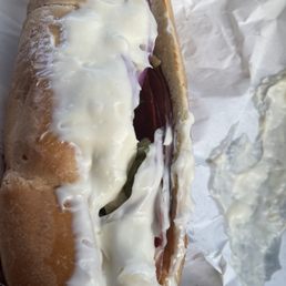 a hand holding a hot dog covered in cheese and onions