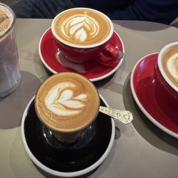 The Beans on Fire - Iced latte, hot latte (red cup), and cortado (black saucer)