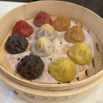 Supreme Dumplings - Sampler platter. Red: spicy. Black: truffle. Yellow: chicken. White with gold on top: wagyu. Orange: crab - Shanghainese Near Me - Honolulu, Hawaii