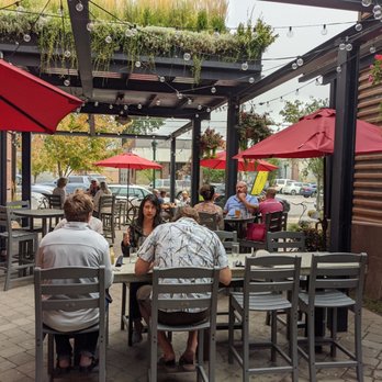 The Fat Pig - a group of people sitting at tables under umbrellas - Pubs Near Me - Sandpoint, Idaho