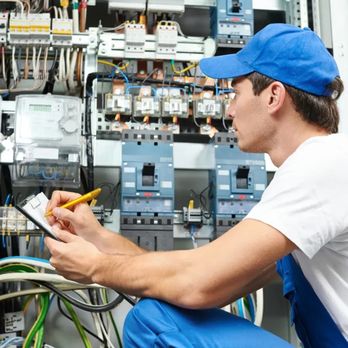 FS Electric - A technician in a blue cap and overalls kneels before a complex electrical panel, meticulously recording data on a clipboard.... - Electricians Near Me - San Francisco, California
