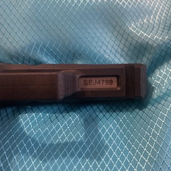 Tempe Trophy - ATF guideline serial number - A black plastic tool or device with a serial number 'SEJ4789' on a label, placed on a blue textured fabric background. - Trophy Shops Near Me - Tempe, Arizona