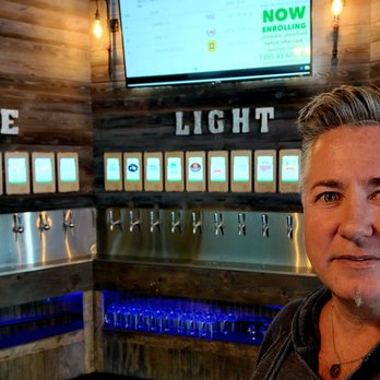 Hops & Berry Taproom - a woman standing in front of a row of taps - Bars Near Me - Williston, North Dakota