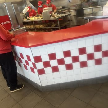 Five Guys - a man standing at a counter in a restaurant - Burgers Near Me - Laurel, Maryland