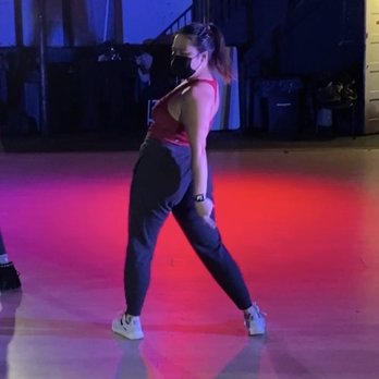 DivaDance - took this during class at culture house DC, I think the choreo was to 34+35 by ariana grande - A woman in a red top, black pants, and sneakers stands in a dance studio with colored lighting, wearing a face mask. - Dance Studios Near Me - Washington, DC, District of Columbia
