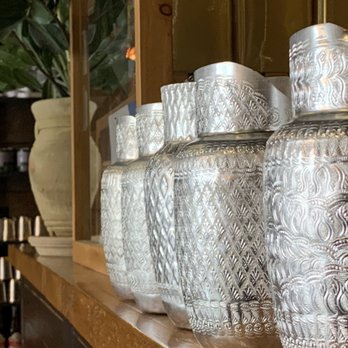 Mae Sri - a row of silver vases on a shelf - Thai Near Me - Montreal, Quebec Mae Sri - a row of silver vases on a shelf - Thai Near Me - Montreal, Quebec
