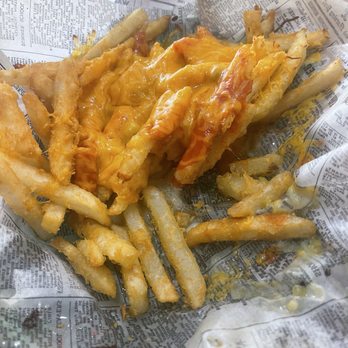 Sergio's Bakery and Cafe - Chile cheese fries - French fries topped with melted cheese and bacon bits are placed on crumpled newspaper-lined paper, suggesting a casual dining or takeout setting. The fries are golden and crispy, with cheese and bacon adding flavor. The paper appears to be used as a liner for serving food, typical of informal food vendors or fast-food establishments. - Bakeries Near Me - Albuquerque, New Mexico