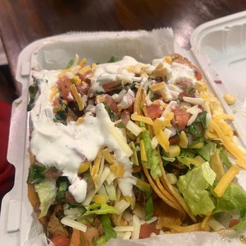 Taco Town - Two tacos filled with lettuce, shredded cheese, diced tomatoes, sour cream, and other ingredients in a takeout container. - Mexican Near Me - Baltimore, Maryland