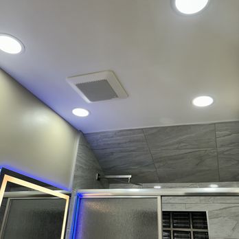 MDF Construction - Interior ceiling with four recessed lights, a ventilation grille, and a gray tiled wall with a window. - Painters Near Me