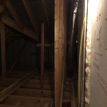 Plus58 Remodeling - Upstairs storage space before - A construction site showing an unfinished attic or ceiling area with exposed wooden beams, insulation, and ductwork. - General Contractors Near Me