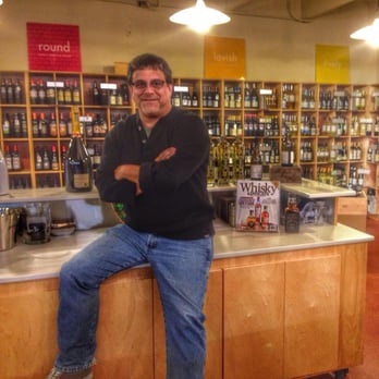 Village Wine and Spirits - a man sitting on a counter - Beer, Wine & Spirits Near Me - Nashville, Tennessee