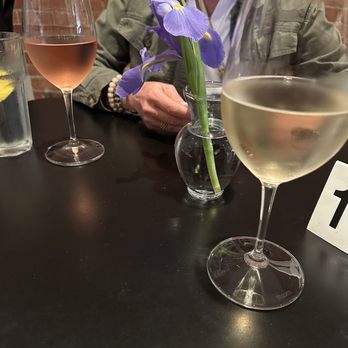 Lucca - a woman sitting at a table with a glass of wine - Italian Near Me - Des Moines, Iowa